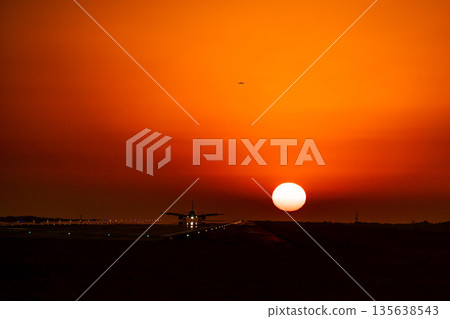 A plane landing with the setting sun behind it 135638543