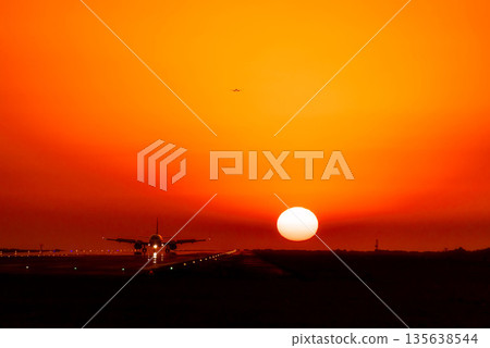 A plane landing with the setting sun behind it 135638544