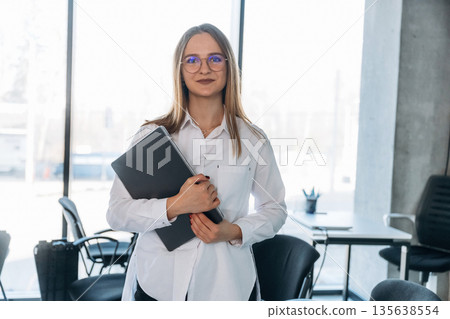 Laptop is in hands. Businesswoman, coach is standing in conference room 135638554