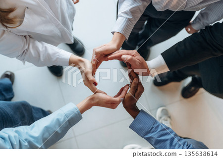 Making circle gesture by hands. Top view of hands of business people that are celebrating success Making circle gesture by hands. Top view of hands of business people that are celebrating success 135638614