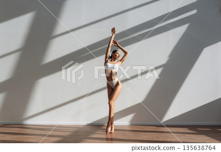 With hands up. Beautiful young woman with slim body type is indoors With hands up. Beautiful young woman with slim body type is indoors 135638764