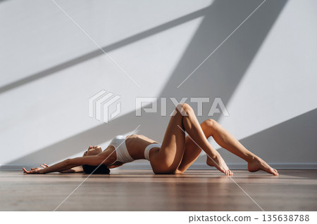 Lying down on the floor. Beautiful young woman with slim body type is indoors 135638788
