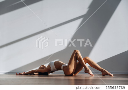Lying down on the floor. Beautiful young woman with slim body type is indoors 135638789