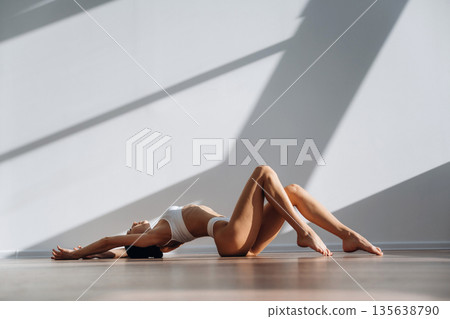 Lying down on the floor. Beautiful young woman with slim body type is indoors Lying down on the floor. Beautiful young woman with slim body type is indoors 135638790