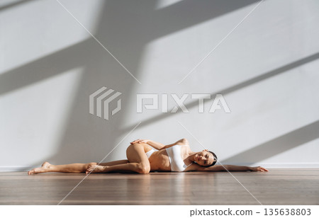 Relaxing on the floor. Beautiful young woman with slim body type is indoors Relaxing on the floor. Beautiful young woman with slim body type is indoors 135638803