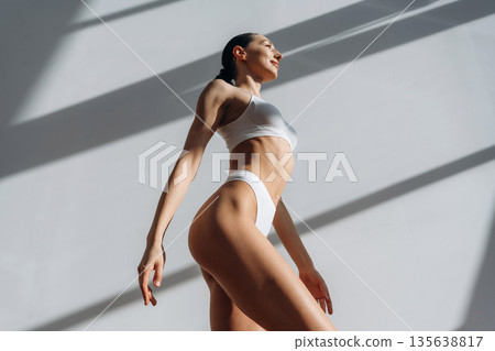 View from below. Beautiful young woman with slim body type is indoors View from below. Beautiful young woman with slim body type is indoors 135638817