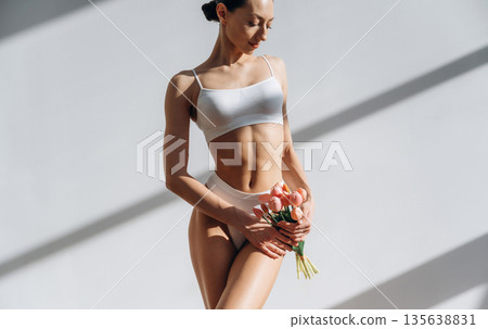 Flowers are in hands. Beautiful young woman with slim body type is indoors 135638831