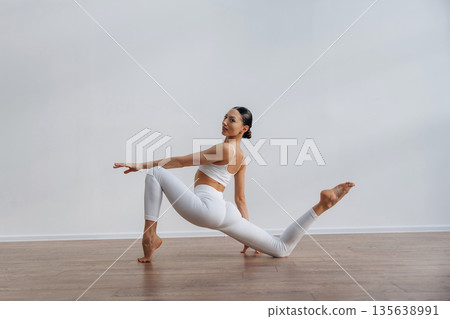 Yoga exercise. Beautiful young woman with slim body type is indoors 135638991