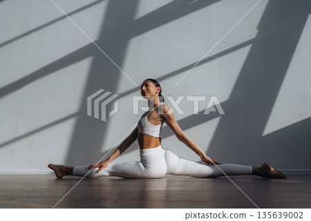 Stretching the legs. Beautiful young woman with slim body type is indoors 135639002