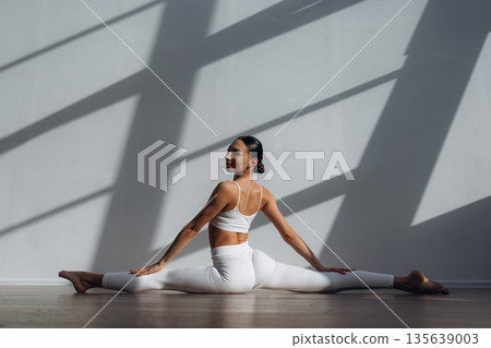 Stretching the legs. Beautiful young woman with slim body type is indoors 135639003