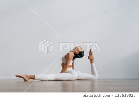 Sportive yoga exercise for flexibility. Beautiful young woman with slim body type is indoors 135639025
