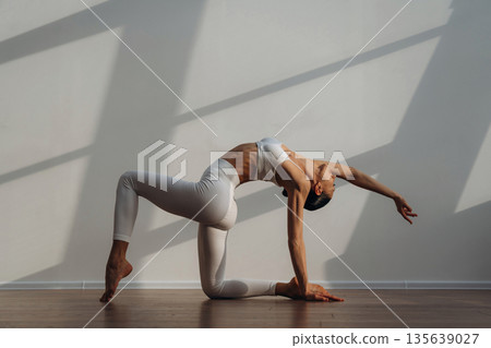 Sportive yoga exercise for flexibility. Beautiful young woman with slim body type is indoors Sportive yoga exercise for flexibility. Beautiful young woman with slim body type is indoors 135639027