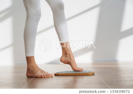 Ready to stand. Close up view of woman's legs that is standing on nails 135639072
