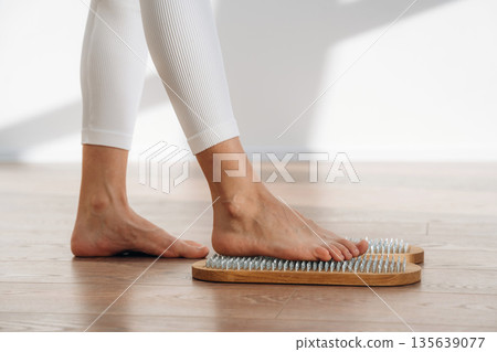 First step. Close up view of woman's legs that is standing on nails First step. Close up view of woman's legs that is standing on nails 135639077