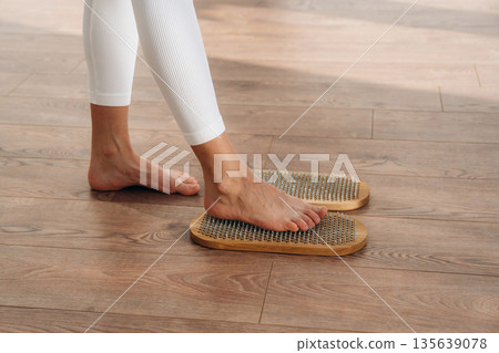 First step. Close up view of woman's legs that is standing on nails First step. Close up view of woman's legs that is standing on nails 135639078