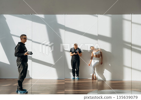 Two photographers and model woman are standing together in the room Two photographers and model woman are standing together in the room 135639079