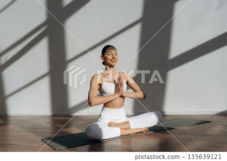 Health care, physical activity, sitting on the floor. Beautiful young woman with slim body type is indoors Health care, physical activity, sitting on the floor. Beautiful young woman with slim body type is indoors 135639121