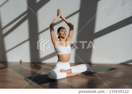 Health care, physical activity, sitting on the floor. Beautiful young woman with slim body type is indoors Health care, physical activity, sitting on the floor. Beautiful young woman with slim body type is indoors 135639122