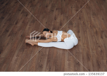 Enjoying doing yoga. Beautiful young woman with slim body type is indoors Enjoying doing yoga. Beautiful young woman with slim body type is indoors 135639137