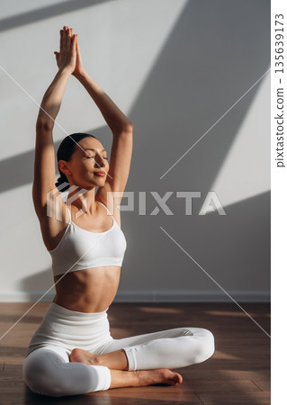 Calm mind, meditation in lotus pose. Beautiful young woman with slim body type is indoors Calm mind, meditation in lotus pose. Beautiful young woman with slim body type is indoors 135639173