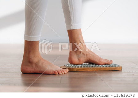 First step. Close up view of woman's legs that is standing on nails First step. Close up view of woman's legs that is standing on nails 135639178