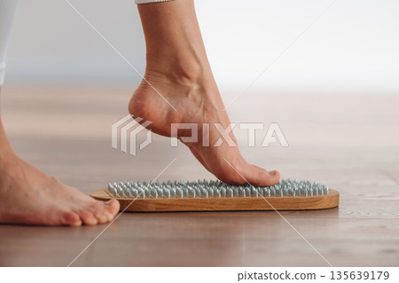First step. Close up view of woman's legs that is standing on nails First step. Close up view of woman's legs that is standing on nails 135639179