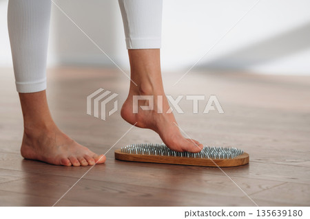 First step. Close up view of woman's legs that is standing on nails First step. Close up view of woman's legs that is standing on nails 135639180