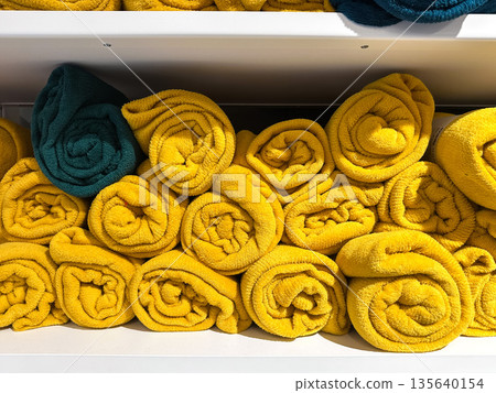 Rolled yellow towels with a single blue one on a shelf. Rolled yellow towels with a single blue one on a shelf. 135640154