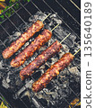 Four grilled kebabs on skewers over a charcoal grill. 135640189