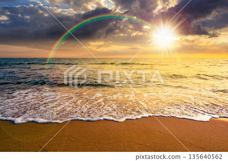 sand beach at the sea for summer vacation concept. beautiful sunset at perfect coast with calm waves and clouds on sky in evening light. scenic landscape for timeless nostalgia book cover with rainbow 135640562