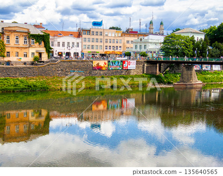 uzhhorod, ukraine - 29 jun, 2007: river uzh on a summer day. uzhhorod city travel background. panoramic view of a historic cityscape with bridge over water. urban landscape of old town in euroope uzhhorod, ukraine - 29 jun, 2007: river uzh on a summer day. uzhhorod city travel background. panoramic view of a historic cityscape with bridge over water. urban landscape of old town in euroope 135640565