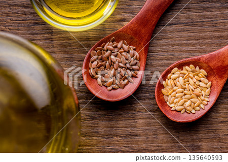 Brown and gold linseed or flaxseed . Healthy flax seed on wooden spoon on wooden table. Top view. Brown and gold linseed or flaxseed . Healthy flax seed on wooden spoon on wooden table. Top view. 135640593