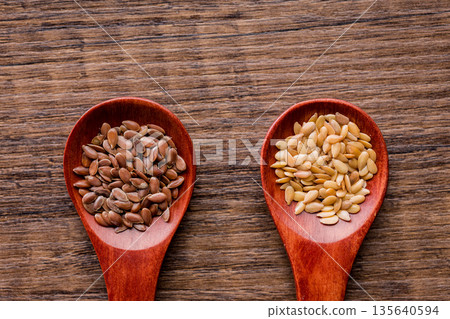 Brown and gold linseed or flaxseed . Healthy flax seed on wooden spoon on wooden table. Top view. 135640594