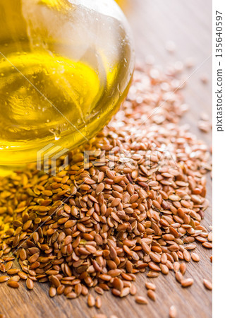 Brown linseed or flaxseed and oil. Healthy flax seed on wooden table. 135640597