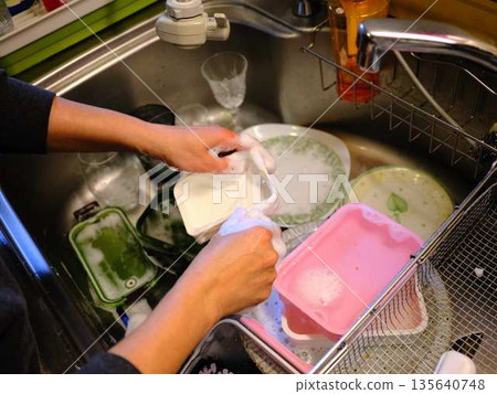 Hands of a woman washing dishes Hands of a woman washing dishes 135640748