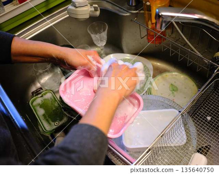 Hands of a woman washing dishes Hands of a woman washing dishes 135640750