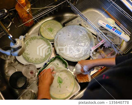 Hands of a woman washing dishes Hands of a woman washing dishes 135640778