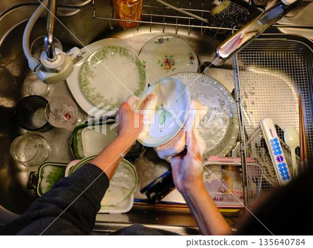 Hands of a woman washing dishes Hands of a woman washing dishes 135640784