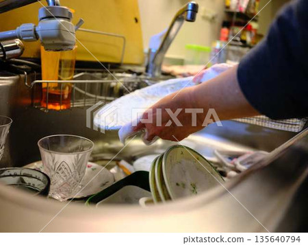 Hands of a woman washing dishes Hands of a woman washing dishes 135640794