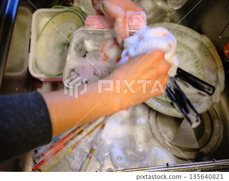 Hands of a woman washing dishes Hands of a woman washing dishes 135640821