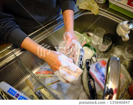 Hands of a woman washing dishes Hands of a woman washing dishes 135640847