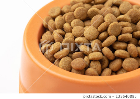 Dry pet food granules in feeding bowl on white background 135640883