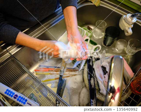 Hands of a woman washing dishes Hands of a woman washing dishes 135640992