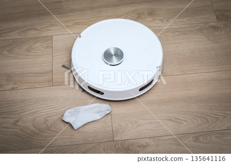 Autonomous Domestic Cleaning Robot Pausing Near Sock On Wooden Flooring 135641116