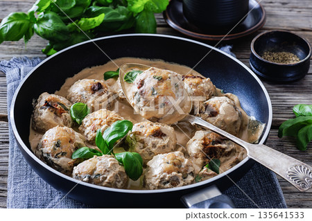 Chicken meatball on spoon over pan with sauce Chicken meatball on spoon over pan with sauce 135641533