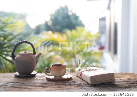 Old earthenware tea pot and gift box with flower on balcony outdoor in winter under Old earthenware tea pot and gift box with flower on balcony outdoor in winter under 135641536