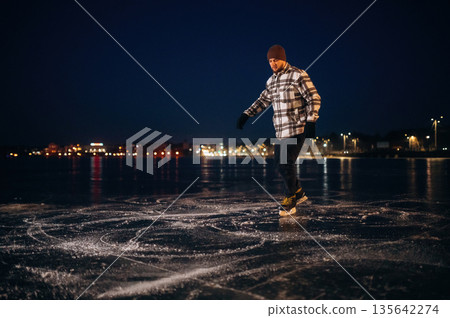 Evening time. A man is on the ice with his skates in winter 135642274