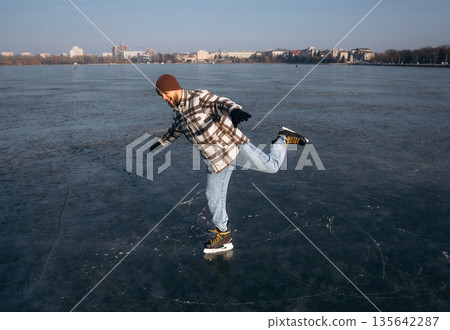Riding on the frozen lake. A man is on the ice with his skates in winter 135642287