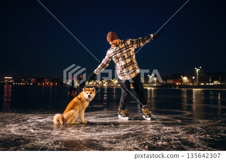 Around the pet, riding. Man with Akita Inu dog is on the ice with skates in winter 135642307