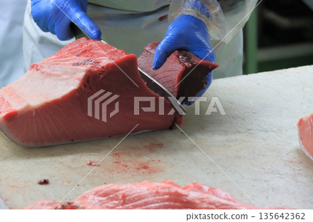 Raw tuna being cut into pieces 135642362
